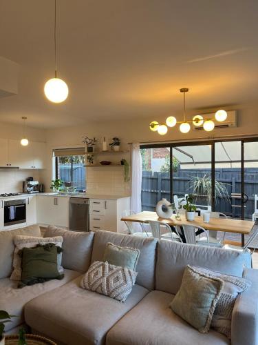 a living room with a couch and a table and a kitchen at Melbourne home close to Airport & Train Station in Melbourne