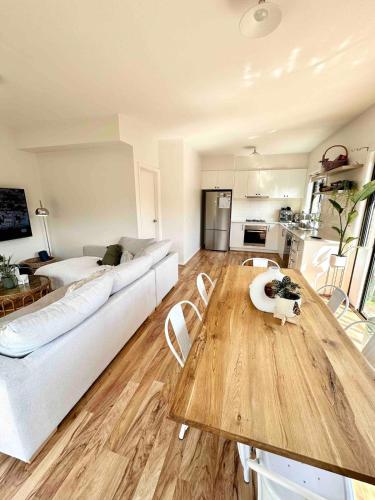 a living room with a white couch and a wooden table at Melbourne home close to Airport & Train Station in Melbourne
