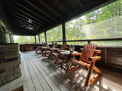 a row of wooden chairs and tables on a porch at Moon Willow - one level cabin with 2 master suites in Walnut Grove