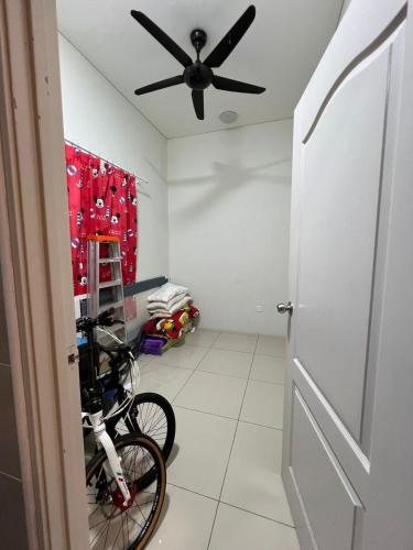a bike parked in a room with a ceiling fan at Shamir Homestay in Lukut