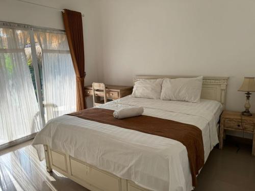 une chambre avec un grand lit avec une grande fenêtre dans l'établissement ATHAYA GUEST HOUSE canggu, à Kerobokan