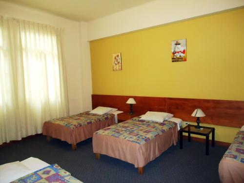 a hotel room with three beds and yellow walls at Novo Bonbini in Lima