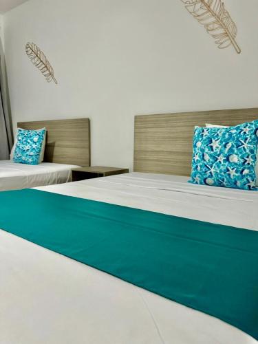 a bedroom with two beds with blue pillows on them at 5th AVENUE oasis 8 personas in Playa del Carmen