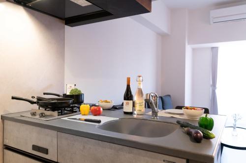 a kitchen with a sink and some bottles of wine at BON Osaka West in Osaka