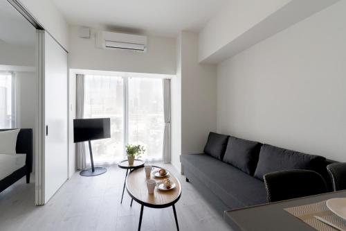 a living room with a couch and a table at BON Osaka West in Osaka