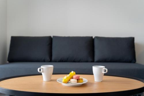 a coffee table with a plate of food and two cups at BON Osaka West in Osaka