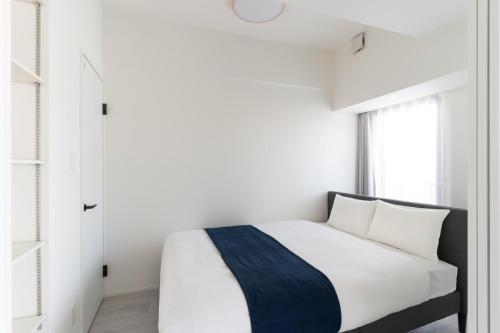 a bedroom with a white bed and a window at BON Osaka West in Osaka