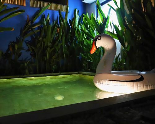 a fake swan sitting in a pool of water at Peacock Private Pool Paradise in Dalung