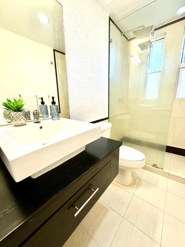 a bathroom with a sink and a toilet and a mirror at 5th AVENUE oasis 8 personas in Playa del Carmen