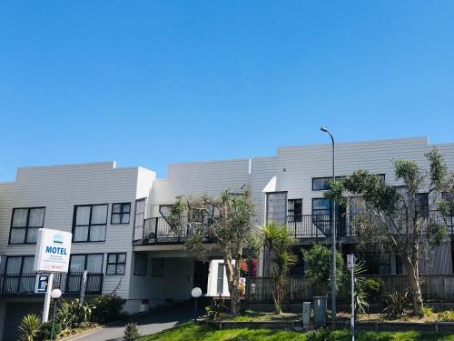 an apartment building with trees in front of it at Wrights by the Sea Motel in Paraparaumu Beach