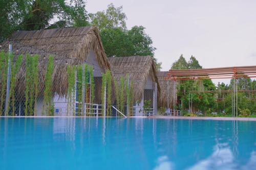 una grande piscina con un edificio con erba di Resort Thái An a Cai Be