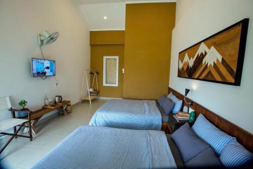 a bedroom with two beds and a couch and a tv at La nha Homestay in Da Lat