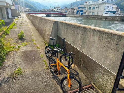 two bikes parked against a wall next to a river at 時端 情緒溢れる西伊豆戸田 人気の古民家一棟貸 ドラッグストア徒歩15秒 海 温泉徒歩5分 自転車2台付 in Toda