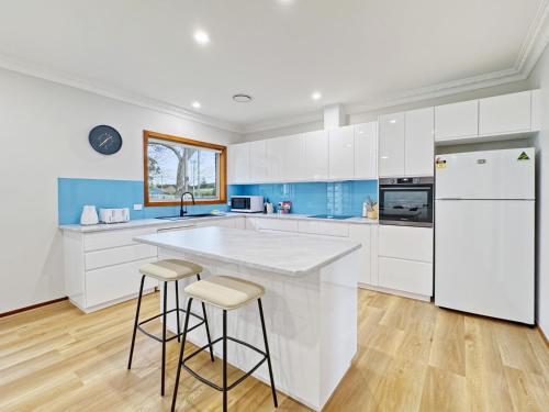 a kitchen with white cabinets and a white refrigerator at 4-Bed Beach House with Garden & Alfresco Dining in Tomakin