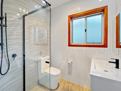 a bathroom with a shower and a toilet and a sink at 4-Bed Beach House with Garden & Alfresco Dining in Tomakin