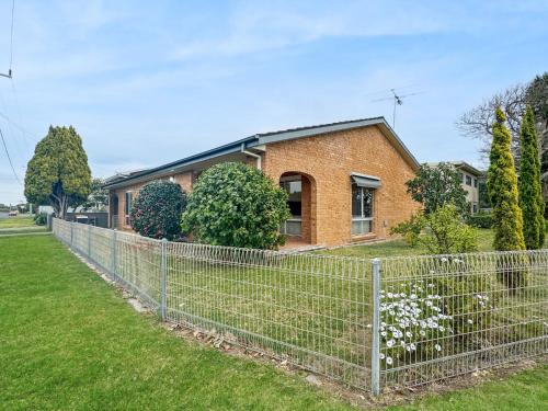 a fence in front of a brick house at 4-Bed Beach House with Garden & Alfresco Dining in Tomakin