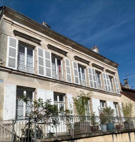 un bâtiment avec des fenêtres blanches à volets et une clôture dans l'établissement La Maison des Ifs Terracotta, à Mamers