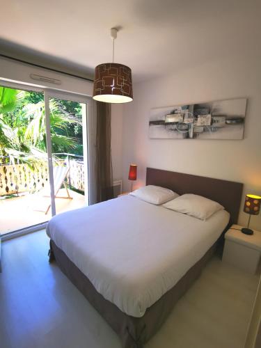 une chambre avec un grand lit et une grande fenêtre dans l'établissement Appartement 90 m2 avec parking terrasse balcons, proche du port et plages, à Arcachon