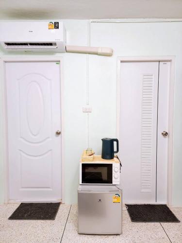 a microwave sitting on top of a refrigerator next to two doors at 807-STP Homely room Free Wi-Fi and Near BTS line in Ban Yang