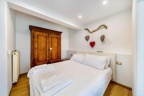 a bedroom with a white bed with a wooden door at Alba's Home Pieve di Cadore in Pieve di Cadore