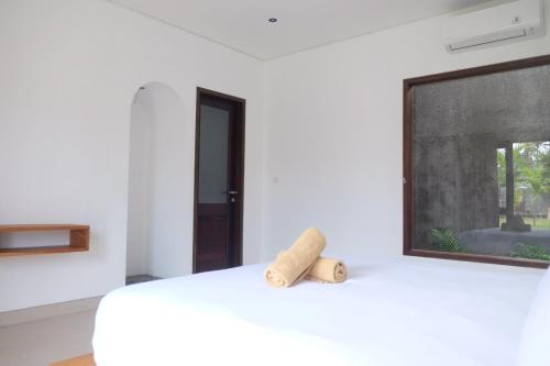 a white room with a bed and a window at Dipenida Bali in Sampalan
