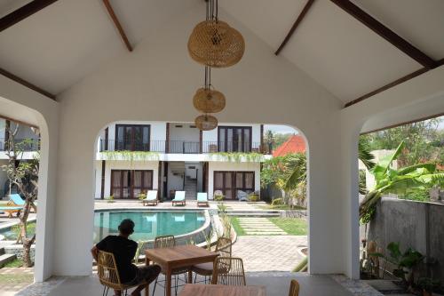 a man sitting at a table next to a pool at Dipenida Bali in Sampalan