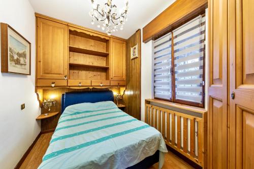 a bedroom with a bed and a chandelier at Alba's Home Pieve di Cadore in Pieve di Cadore