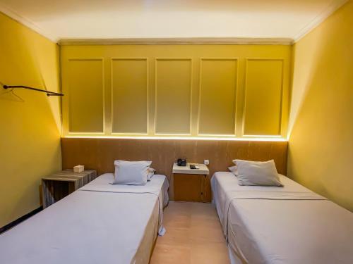 two beds in a small room with yellow walls at Grand mansion hotel in Blitar