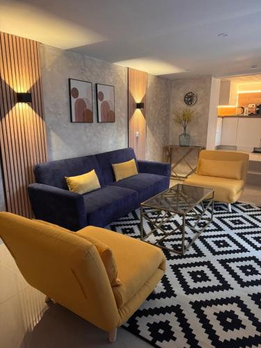 a living room with a blue couch and yellow chairs at Appartement Love in Bussières-lès-Belmont