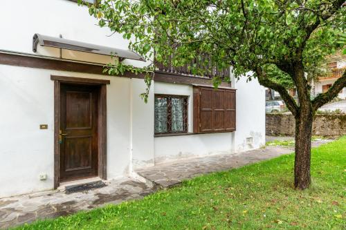 a house with a door and a tree at Alba's Home Pieve di Cadore in Pieve di Cadore