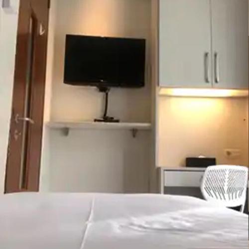 a bedroom with a bed and a tv on a wall at Bening Boutique Hotel Managed By Salak Hospitality in Cibening Tiga