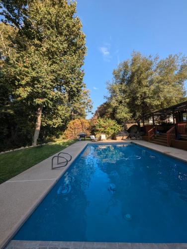 a large blue swimming pool in a yard with trees at Sequoia Zen River House in Three Rivers