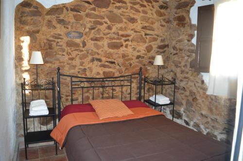 1 dormitorio con 1 cama frente a una pared de piedra en Finca Los Caleros, en Juan Gallegos