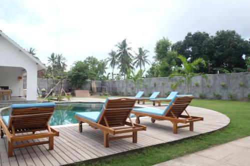 a group of lounge chairs and a swimming pool at Dipenida Bali in Sampalan