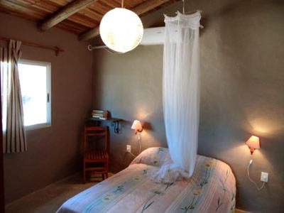 une chambre avec un lit muni d'une moustiquaire dans l'établissement Amatista, à Punta del Diablo