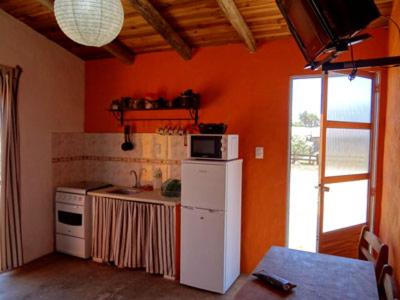 a kitchen with orange walls and a white refrigerator at Amatista in Punta Del Diablo