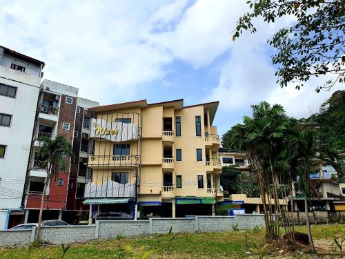 a yellow building in front of some buildings at Royal Waves Hotel in Patong Beach