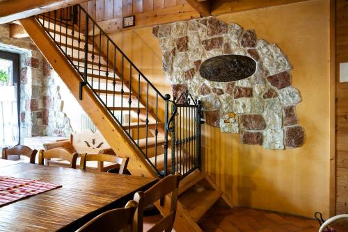 a dining room with a staircase and a stone wall at Baita Chalet Alabama in Arsiè