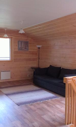 a living room with a couch in a wooden room at Rautjärvi Cottage in Kokkola