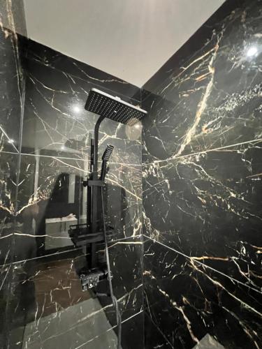 La salle de bains est pourvue d'une douche et d'un mur en marbre noir. dans l'établissement Appartement cosy Centre-ville, à Roubaix