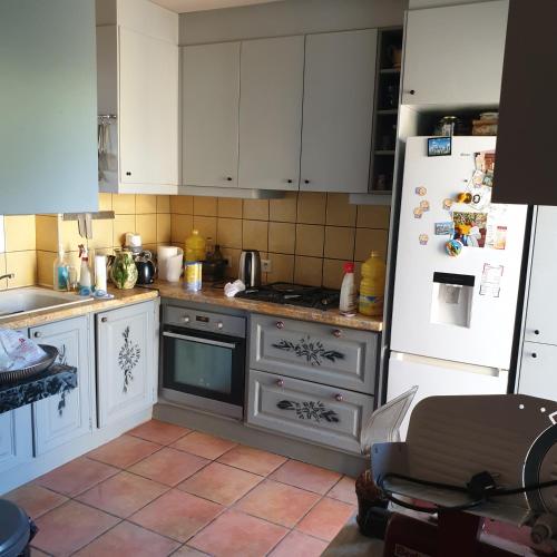 une cuisine avec des armoires blanches et un réfrigérateur blanc dans l'établissement Pied a terre plein de verdure, à Vendargues