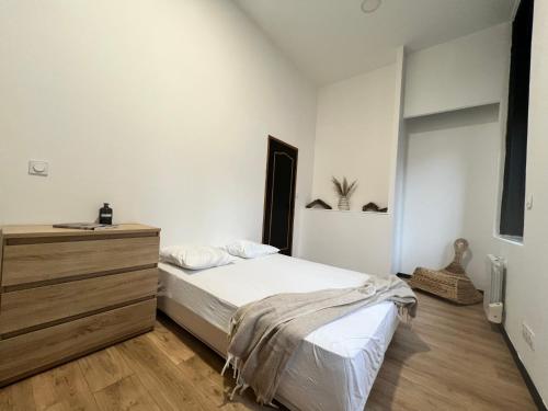 une chambre avec un lit et une commode en bois dans l'établissement Appartement cosy Centre-ville, à Roubaix