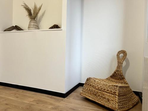 une corbeille en rotin assise sur un sol à côté d'un mur dans l'établissement Appartement cosy Centre-ville, à Roubaix