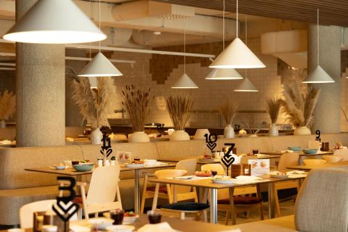 a restaurant with tables and chairs and pendant lights at Instytut Zdrowia Sofra FIT & SPA in Mielno