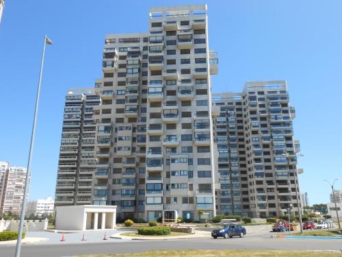 un edificio de apartamentos alto con coches estacionados frente a él en Parquemar Center I, en Punta del Este