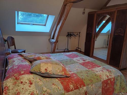 a bedroom with a bed with a quilt and a window at Gîte : La Cochetière : ancienne ferme 18éme in Le Grais