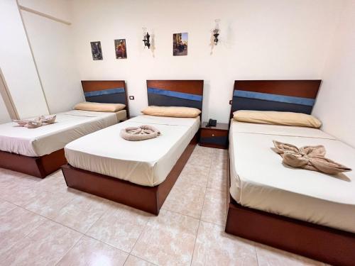 three beds in a room with white walls at Reef House in Marsa Alam City