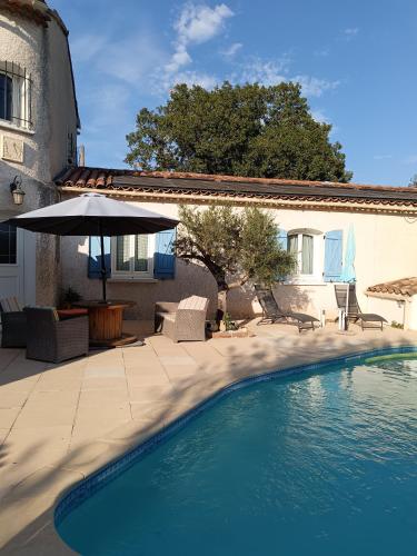 - une piscine à côté d'une maison avec un parasol dans l'établissement CHEZ BETTY, au Luc