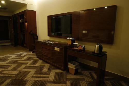 a hotel room with a television and a desk with a telephone at Royal Swiss Lahore in Lahore