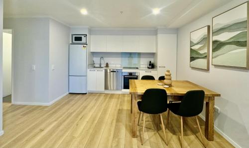 a kitchen and dining room with a wooden table and chairs at Central City Apartment 'The Olive' in Christchurch